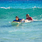 Surf instructeur duwt surfen student in de golven